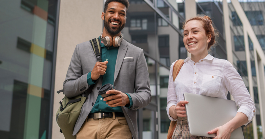 Two students smiling and walking on the street.