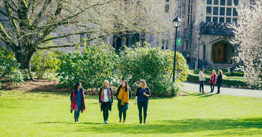 4 people walking across the lawn in front of hatley castle