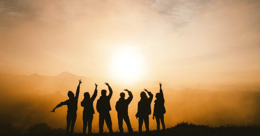 group in silhouette reaching for sky