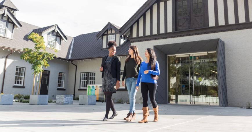 Three students walk outside of the Sherman Jen Building on campus. 