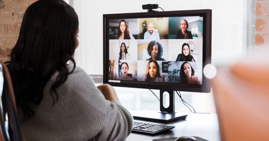 A woman can be seen from behind looking a screen during a video conference.