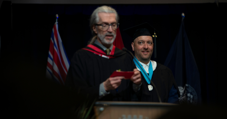 A graduate wears a medal while on the convocation stage.