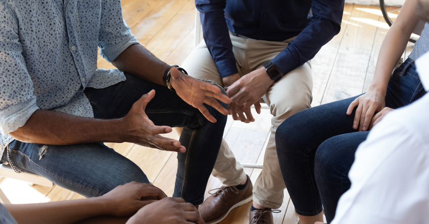 A group of people seating in a circle engaged in conversation