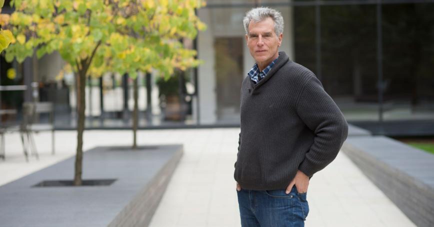 Thomas Homer-Dixon stands in front of a modern building with hands in pockets