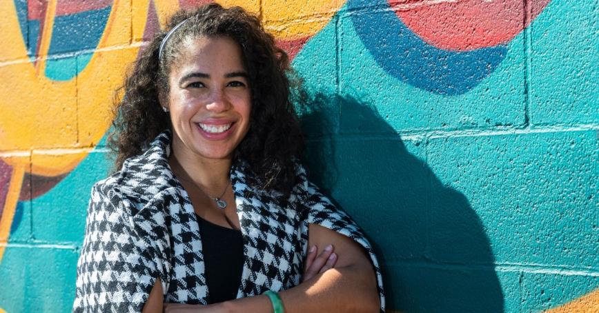 Odion Welch stands in front of a colorful mural