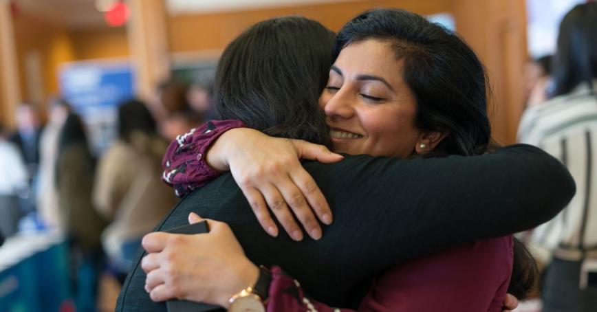 A student hugs a supporter in celebration in a crowded room