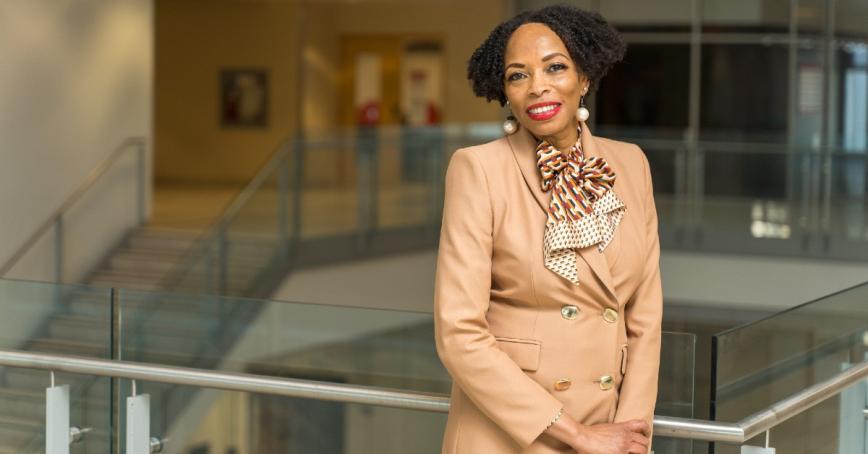 Professor Andrea A. Davis standing on staircase, smiling at camera.