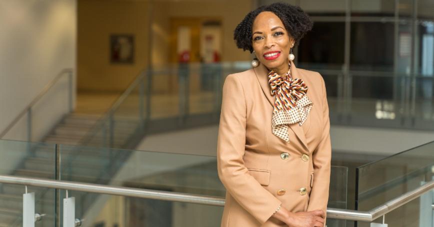 Professor Andrea A. Davis standing on staircase, smiling at camera.