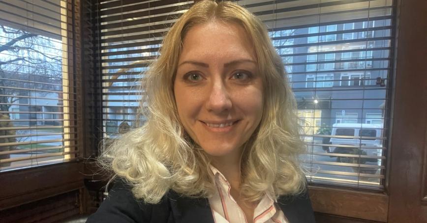 Smiling woman looks directly into the camera; office setting background