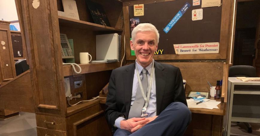 Wolfgang Depner sits at his desk in the legislature, wearing a suit and tie. 