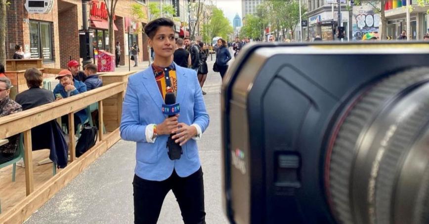 Iman Kassam stands in downtown Montreal in front of a camera, holding a CTV microphone.