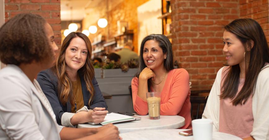 four people sitting around a table talking