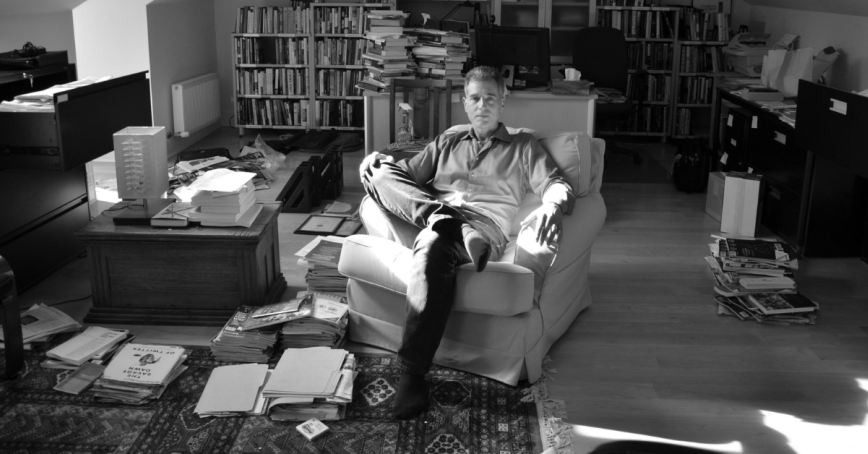 A black and white photo of a man sitting in his office.