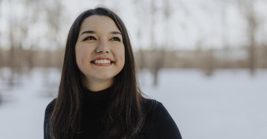 Andrea Juárez stands in front of a snowy background smiling. Photo credits to Aron Diaz. 