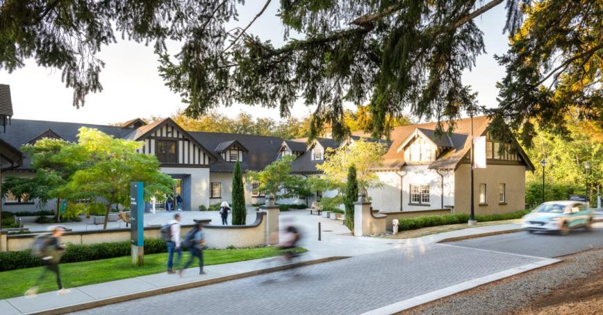 Students whir by on foot and bicycle past the Sherman Jen Building.