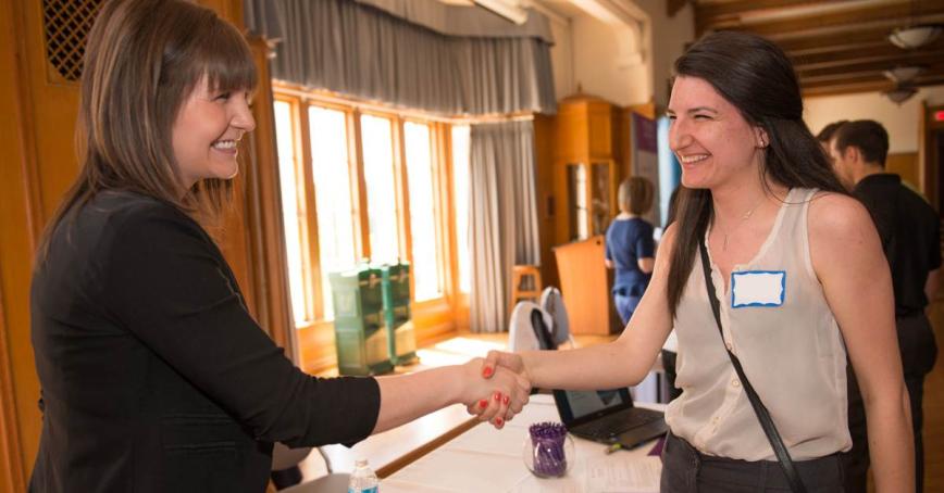 Two Royal Roads University students shake hands at a career learning event.