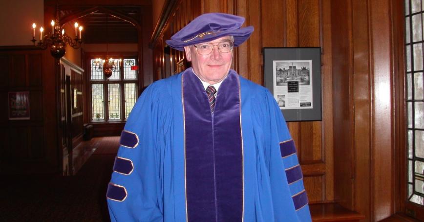 Hugh Gordon smiling at camera wearing academic regalia.