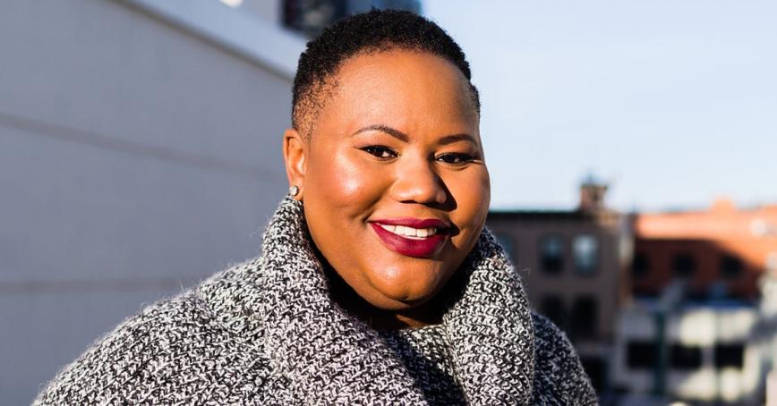 Isha Thompson smiling at the camera, wearing a black and white sweater.