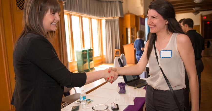 student shaking hand with an employer, both smiling