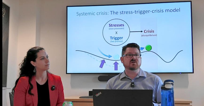 Megan Shipman and Michael Lawrence seated in front of a large presentation screen.