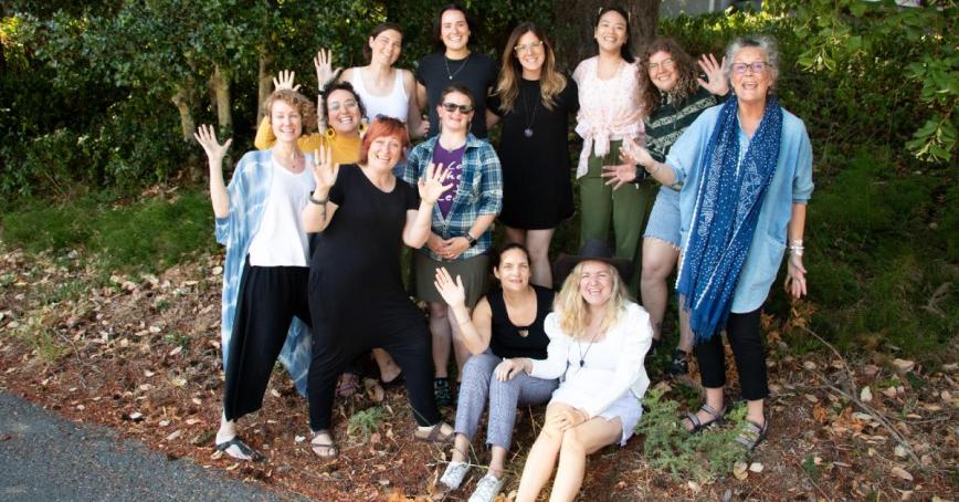 Masters students with Hilary Leighton standing in front of a large tree and waving at the camera.