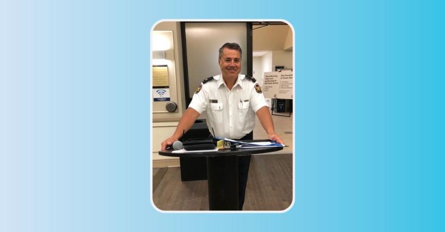 Michael Souliere standing at a podium, wearing his police uniform.
