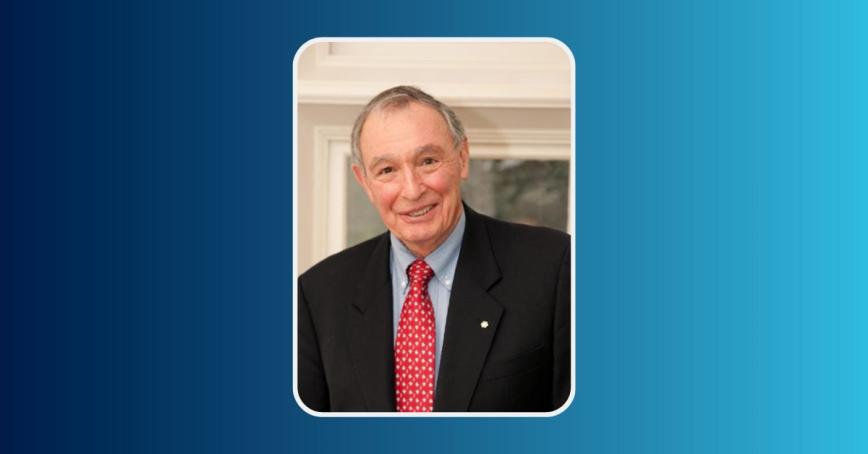 A man wearing a formal blue jacket and shirt offset by a red tie