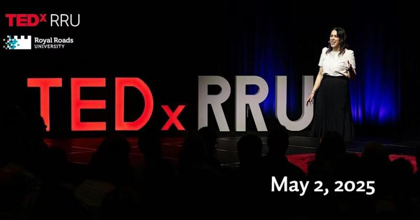 A presenter stands on the TEDxRRU stage, beaming her story into the darkness. 