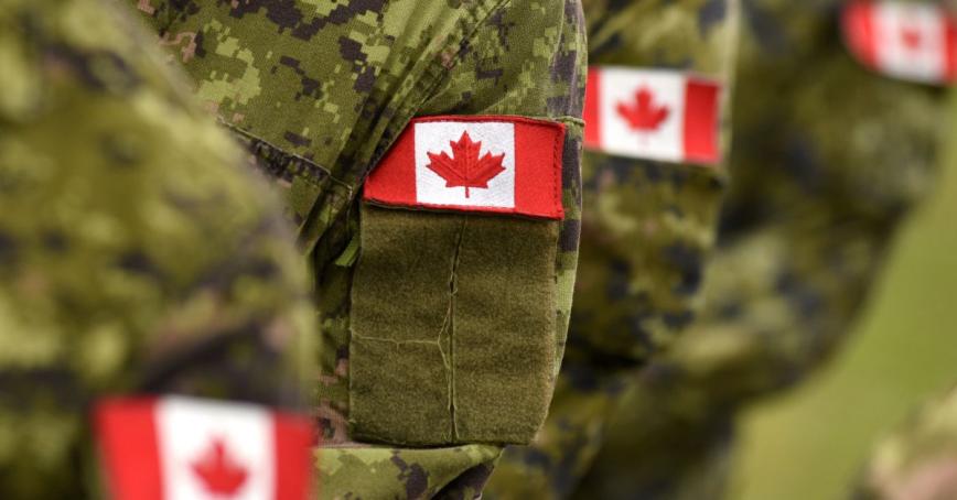 Small embroidered Canadian flag badges on the left sleeve of green military fatigues