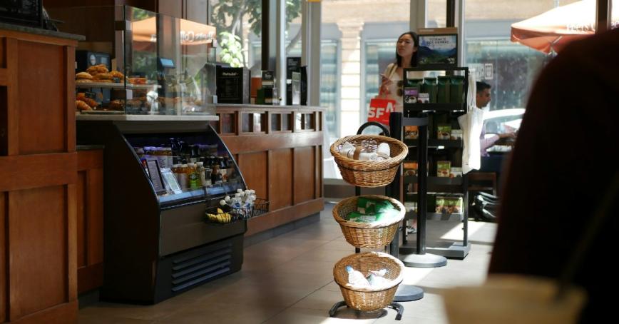Cafe with coolers and grab and go items, a woman is looking at the food options.