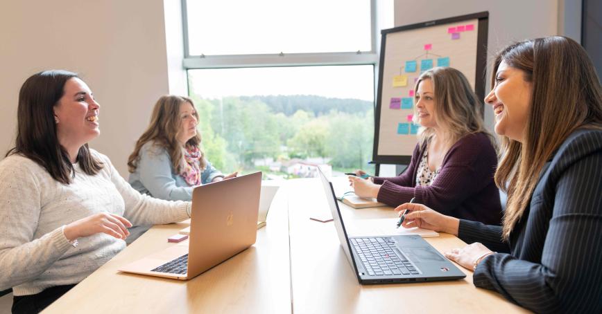 4 students sitting at a table laughing