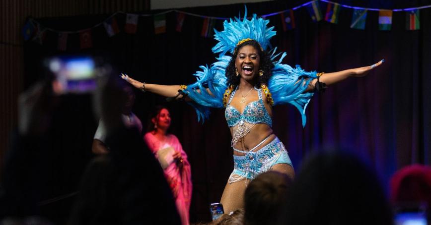A woman performs during the RRU Global Showcase. She's wearing a two piece sparkly blue costume and a headress.
