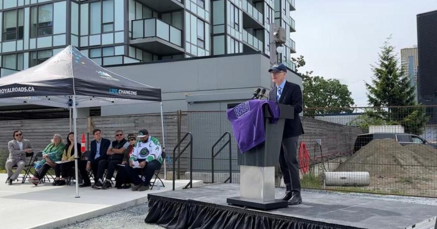 Royal Roads president Philip Steenkamp stands at a podium in front of the new RRU Langford campus