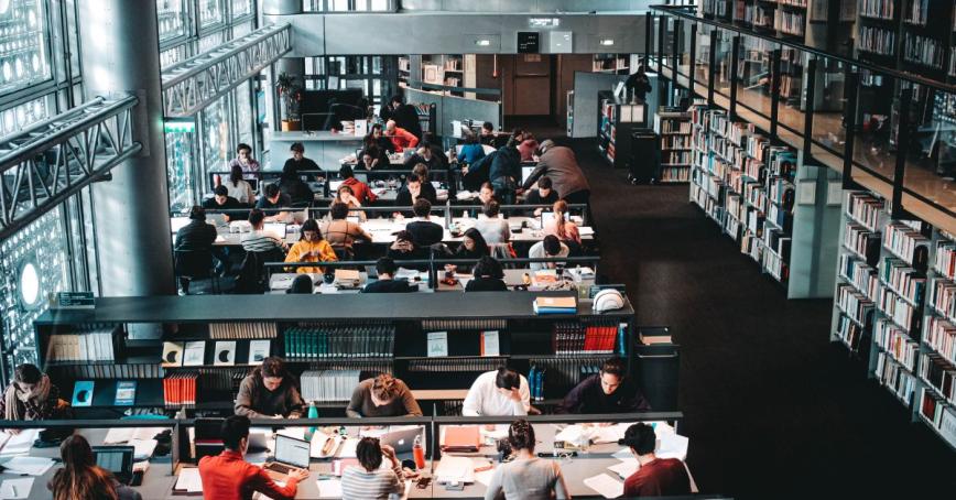 A modern library in a university setting with students at tables studying