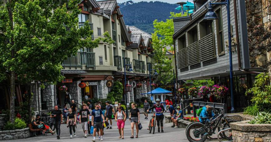 Whistler Village in summer with tourists walking along the streets in summer attire.