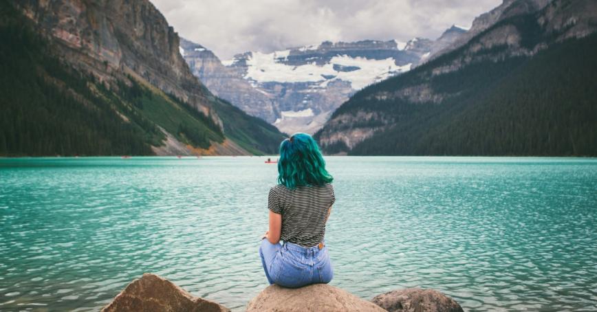 Woman sitting on a rock gazing out over Lake Louise.