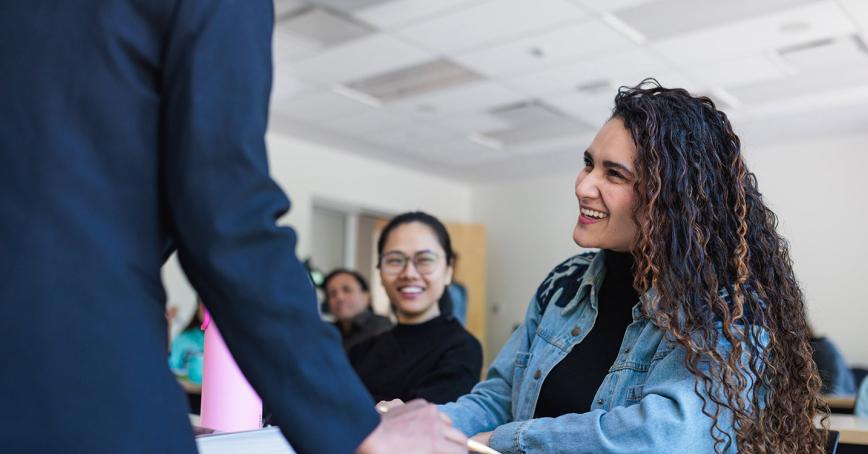 A student looks up at their instructor in a classroom setting