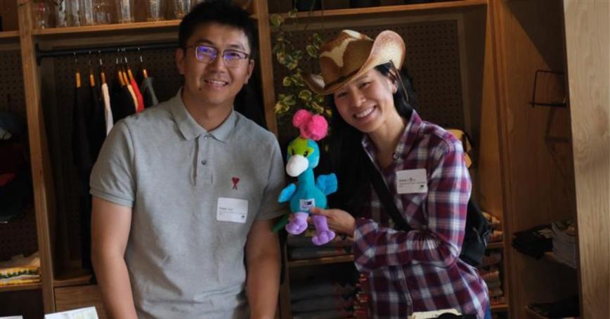 Two Royal Roads staff members standing with a peacock stuffie