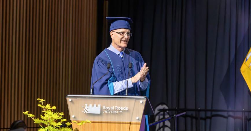 Philip Steenkamp standing on stage at Spring 2025 Convocation, wearing academic robe and clapping
