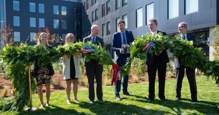 Partner and government representatives join to cut a green cedar bough with large shears