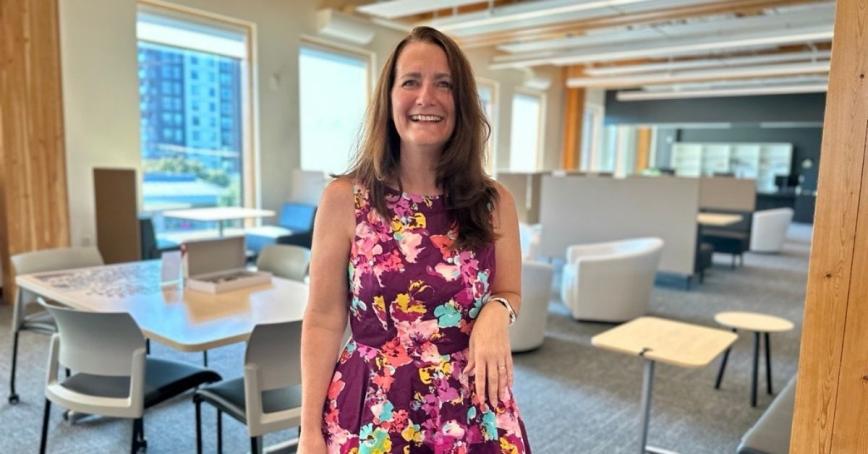 A woman smiles while standing in a library.