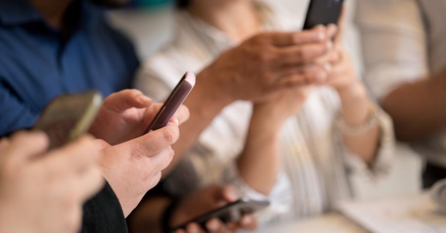 The hands of three people texting on smart phones
