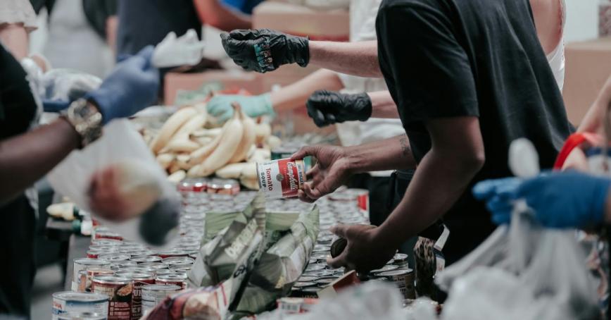 Volunteers at a food bank organizing a table full of cans 