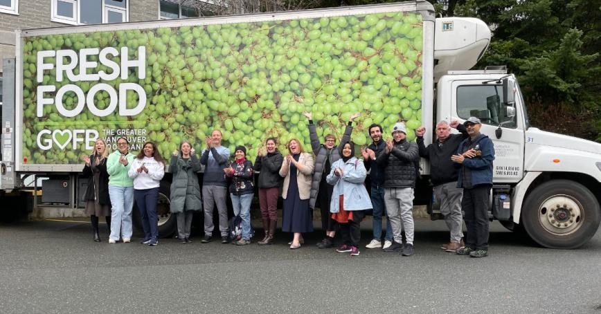 A group of people lined up in front of a big delivery truck