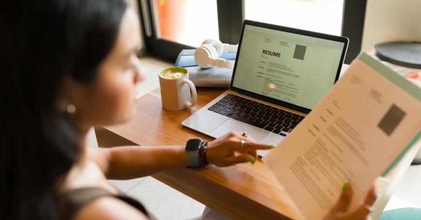 A young woman sitting in a cafe looking at a resume