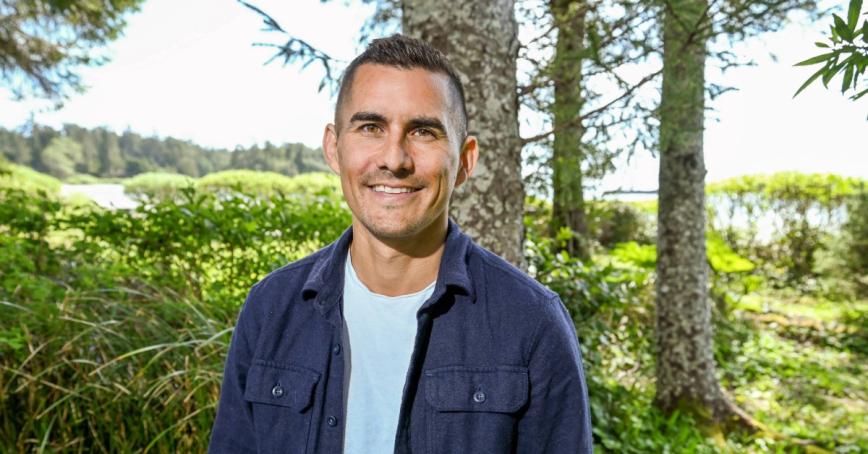 Tyson Atleo stands in front of a coastal forest