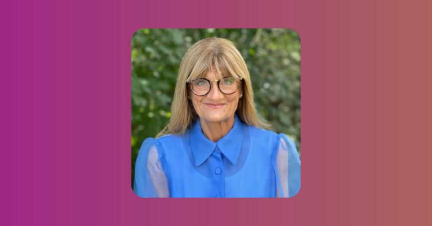 Kathy Cowan Sahadath wearing a blue blouse and dark-rimmed glasses.
