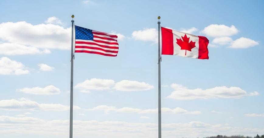 Two flagpoles beside each other with the US flag and the Canadian flag. 