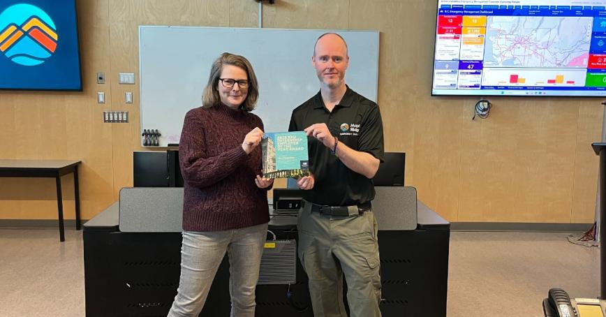 Dawn Varley and Edd Bennett standing in a boardroom hold Internship of the Year award.