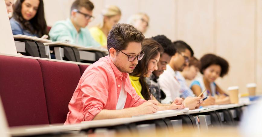 Students sit in a lecture theater, taking notes
